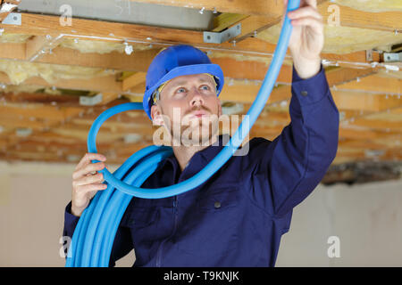 plumber checking ceiling pipes Stock Photo