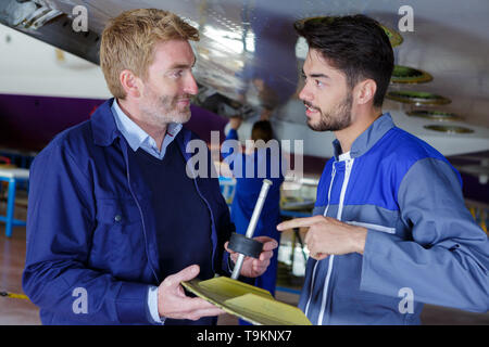 two flight engineers talking in a large aircraft hangar Stock Photo