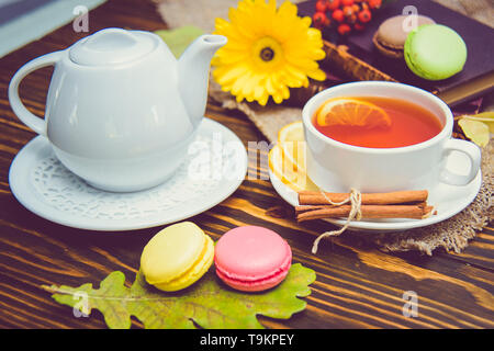 A cup of black tea with macaroons and lemon on the table. Stock Photo