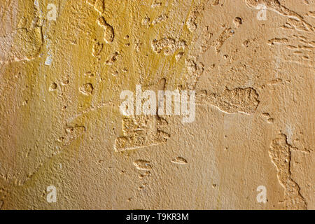 Close-up of colorful golden bronze plastered uneven stucco wall. Abstract texture, chaotic copy space background. Decorative grunge space. Stock Photo