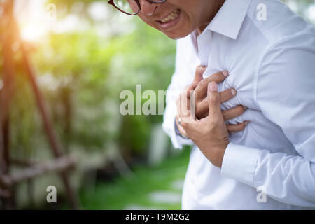 Asian man having chest pain - heart attack close up - Image Stock Photo