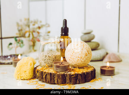 Side view of home wellness spa products, orange bath bomb, aroma bath salt, sea sponge, tea candles lit. Very zen set, tree of love and amethyst cryst Stock Photo