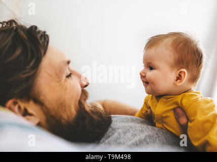 Father and his baby daughter talking playing together family home lifestyle dad and child parenthood concept Stock Photo