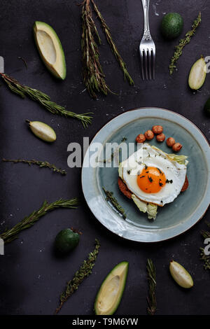 Top view of healthy breakfast scrambled eggs with bread and nuts in a plate on black background with avocado, rosemary, lime. Top view. Flat lay. Heal Stock Photo