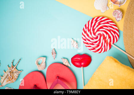Beach accessories on sky blue and yellow background with copy space. Flat lay composition of pink flip flops, seashells, towel, hat, sunglasses and tw Stock Photo