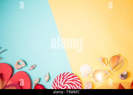 Beach accessories on mint and yellow background with copy space. Flat lay composition of pink flip flops, seashells, hat, sunglasses and lollipop. Sum Stock Photo