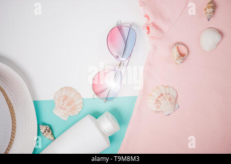 Flat lay composition with sunglasses, seashells, sunscreen, pink t shirt, straw hat. Beach accessories on white light blue background. Summer, vacatio Stock Photo