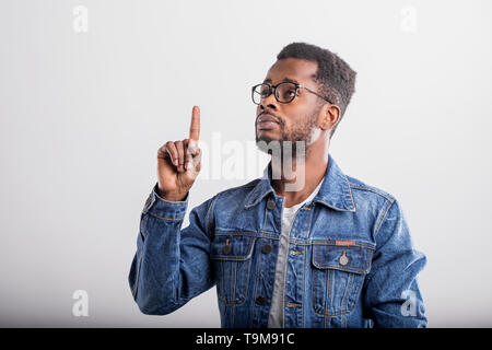 Studio shot of thoughtful clever african student, manager in casual clothes raising index finger in eureka gesture, having exellent idea how to make i Stock Photo