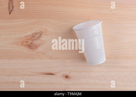 White plastic Cup is on a wooden table of natural color. the concept of the end of the party and the rejection of plastic utensils Stock Photo