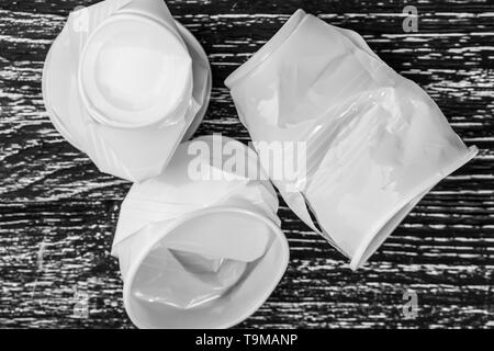 White plastic cups crumpled on a black wood table. The concept of life without plastic Stock Photo