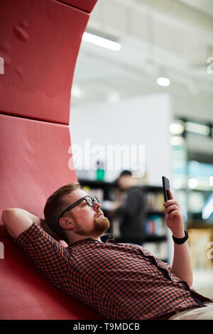 Relaxed man reading book on smartphone Stock Photo
