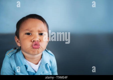 Young boy puckering up his lips to give a kiss and wearing a light blue vintage shirt. Stock Photo