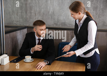 Young waitress with menu on tablet PC screen in restaurant Stock Photo