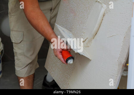 Spreading wet mortar before applying tiles on bathroom floor tile. Stock Photo
