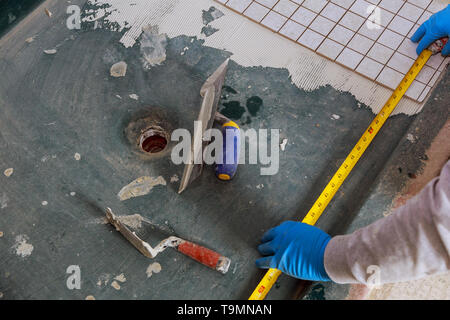 Plaster repair work laying tile, trowel in a man worker using measuring and marking Stock Photo