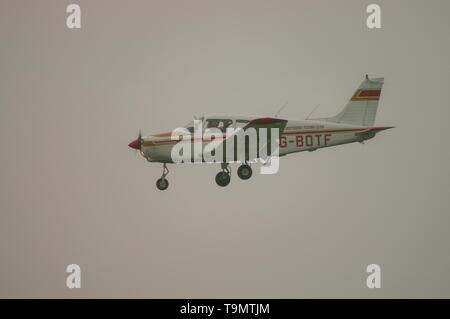 PIPER PA-28-151 Cherokee Warrior light plane landing in bad weather. Private pilot flying in fog, foggy sky. Low cloud Stock Photo