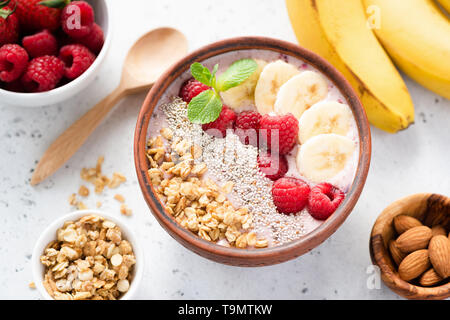 Smoothie bowl with superfoods chia seed, granola, banana and raspberry on top. Healthy vegan vegetarian food Stock Photo
