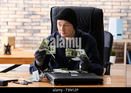 Male thief stealing briefcase with money in office Stock Photo