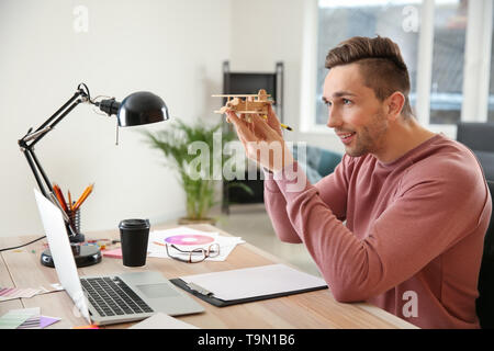 Young designer with airplane model working in office Stock Photo