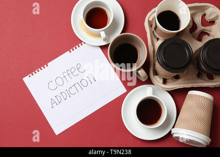 Almost empty cups of coffee and paper sheet with text COFFEE ADDICTION