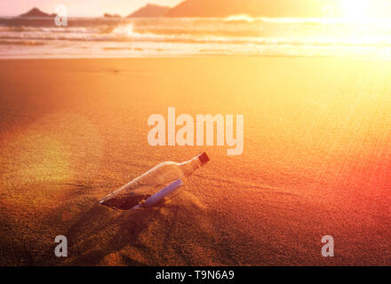 Message In A Bottle Glass Corked On Ocean Beach At Golden Sunset Conceptual Stock Photo