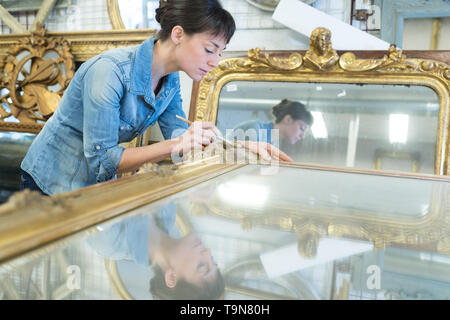 female artisan working on a big wooden picture frame Stock Photo
