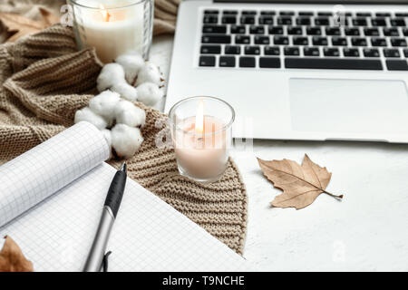Laptop, open notebook and burning candles on white wooden table Stock Photo