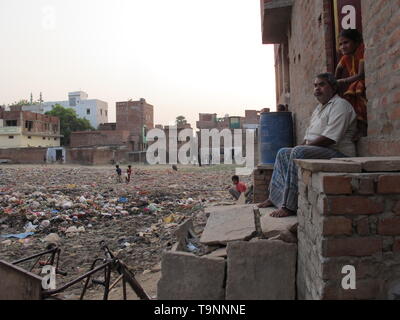 Varanasi, India. 26th Apr, 2019. Mohammad Shabbir, a physically challenged man, sits outside his home in Saraiya, Varanasi, overlooking a yard with piles of rubbish, overflowing drains and children playing in squalid conditions. Residents of Muslim-dominated quarters allege they have been neglected by authorities and suffer lack of development and utility services including drinking water supplies and sanitation. Credit: Siddhartha Kumar/dpa/Alamy Live News Stock Photo
