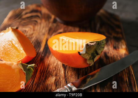 Sliced ripe persimmons on wooden board, closeup Stock Photo