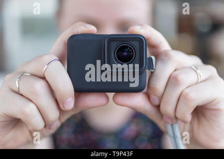 Woman's hands close up holding a small black action camera taking a video or photo Stock Photo