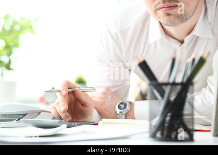 Hand of male clerk hold silver pen using calculator Stock Photo