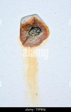 White concrete wall with rusted hole. Rust big dent on the roughness old house wall Stock Photo