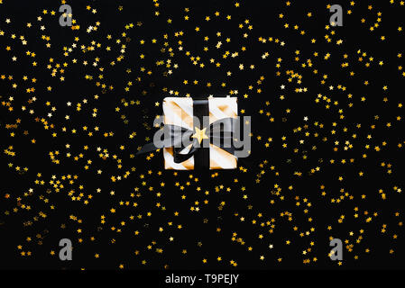 Star shaped golden sequins on a black background. Stock Photo