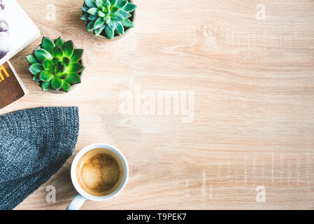 Top view of cosy home scene. Books, woolen blanket, cup of coffee and succulent plants over wooden background. Copy space. Stock Photo