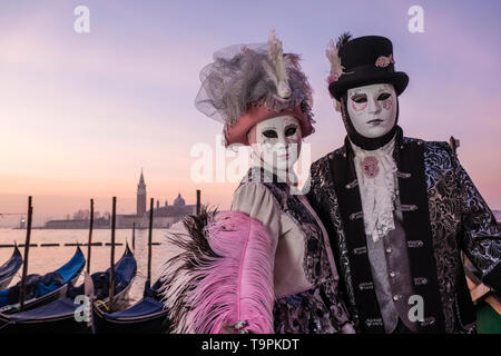 Portraits of a masked couple in beautiful creative costumes, posing at Grand Canal, Canal Grande, celebrating the Venetian Carnival Stock Photo