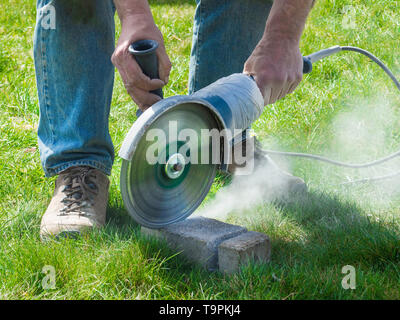 A worker cuts concrete brick circular saw at a construction site outdoor Stock Photo