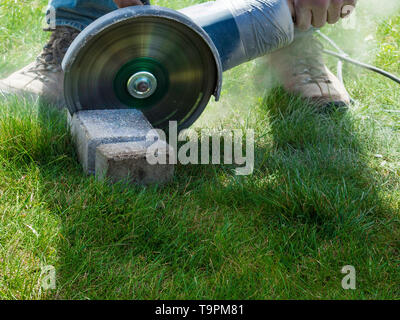 grinder worker cuts a stone brick the electric tool outdoor Stock Photo
