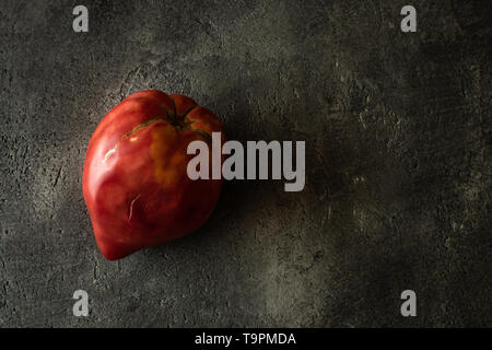 Organic Heirloom Tomato on Rustic Dark Background. Red Bull's Heart. Stock Photo