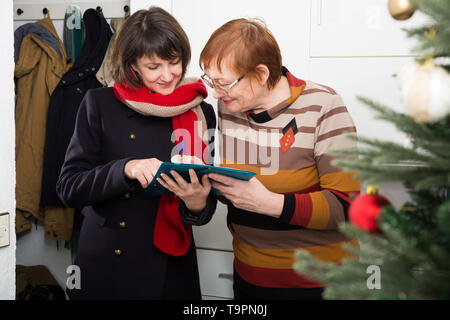 Positive mature woman answering questions of female interviewer at her home for New Year holiday Stock Photo