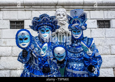 Portraits of a masked couple in beautiful creative costumes, posing in front of a house facade, celebrating the Venetian Carnival Stock Photo