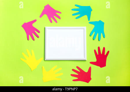 Colourful Painted Hands around white frame on green background. Family concept. Symbol unity, growth, ready for your logo. Expressing Positivity Conce Stock Photo