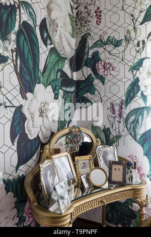 Vanity table with mirror  in the corner of a bed room with wallpaper on the wall Stock Photo