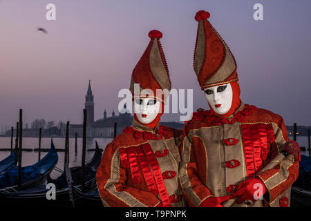 Portraits of a masked couple in beautiful creative costumes, posing at Grand Canal, Canal Grande, celebrating the Venetian Carnival Stock Photo