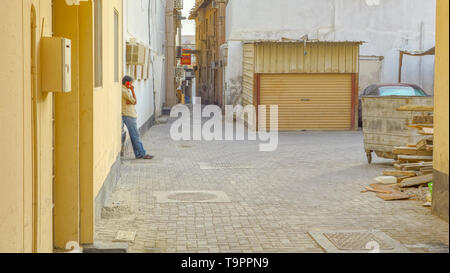 Man talking on the phone in a traditional neighborhood, Muharraq, Barhain Stock Photo