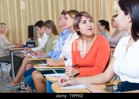 Young female student lively talking with her groupmates during classes in lecture hall Stock Photo