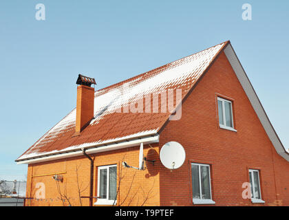 Red metal roof tile and chimney covered with snow Stock Photo