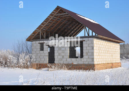 Building new house from autoclaved aerated concrete blocks vs bricks with unfinished roofing metal tiles construction. Stock Photo