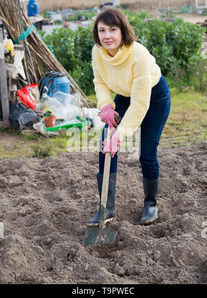 Woman using shovel for digging oil in garden Stock Photo