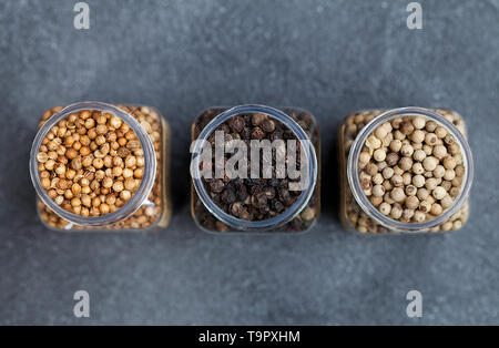 Black, white pepper, peppercorns, coriander seeds in jars. Top view. Copy space. Stock Photo