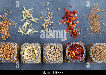 Assortments of spices in jars on grey stone background. Top view. Copy space. Stock Photo